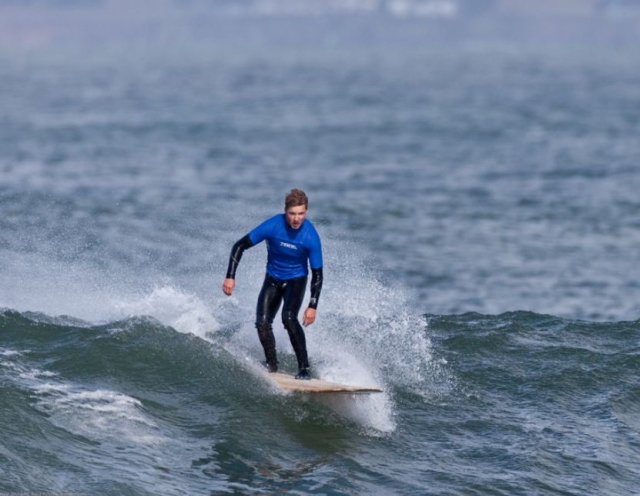  Surfer mit Neoprenanzug auf dem Brett 
